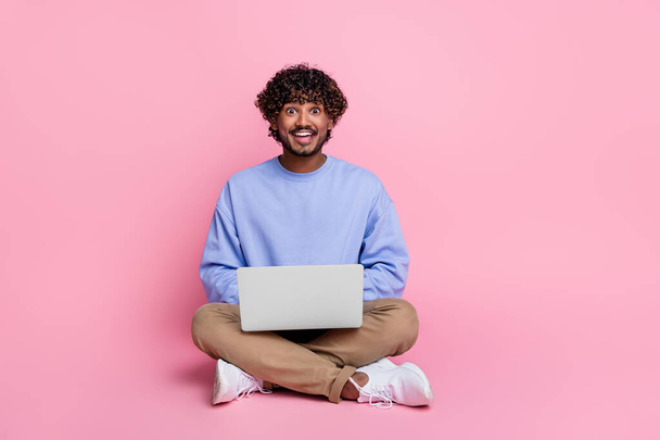 Full size photo of nice young guy sit floor excited netbook eshopping dressed stylish blue outfit isolated on pink color background. - Φωτογραφία, εικόνα