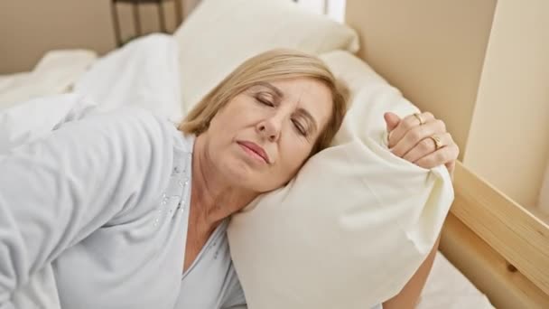 Kypsä valkoihoinen nainen nukkuu rauhallisesti kevyessä makuuhuoneessa, jossa on rentoutumista, tyyneyttä ja mukavuutta.. - Materiaali, video