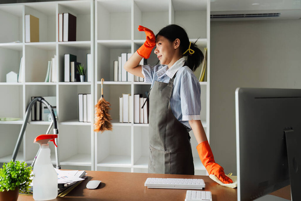 Femme femme de ménage sourire et portant un gant, se préparant à nettoyer le bureau. - Photo, image