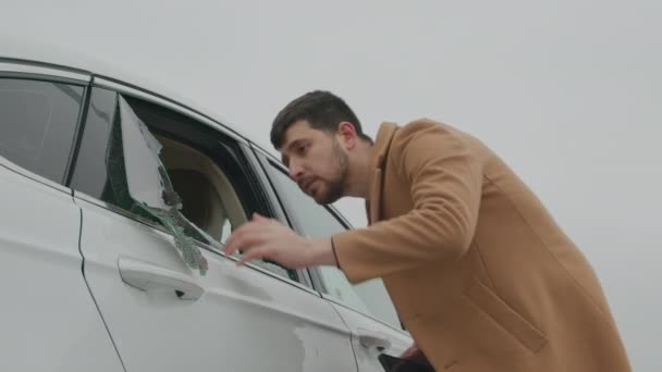 Un hombre sorprendido notando la ventana destrozada del coche, haciendo una llamada de emergencia. El dueño del coche descubriendo la ventana rota. - Imágenes, Vídeo
