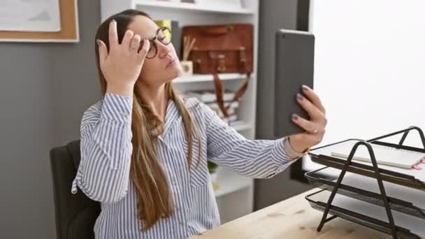 Sebevědomá žena v pruhované košili vezme selfie se svým smartphonem v moderním kancelářském prostředí. - Záběry, video