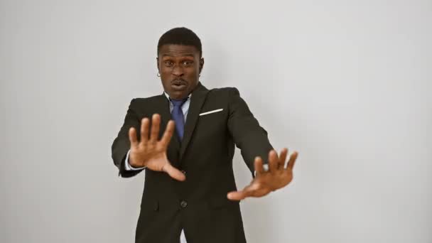 Σοκαρισμένος Αφροαμερικάνος επιχειρηματίας με κοστούμι, τρομοκρατημένος και φωνάζοντας πανικόβλητος, κάνοντας χειρονομίες να σταματήσουν με τα χέρια στο λευκό φόντο - Πλάνα, βίντεο
