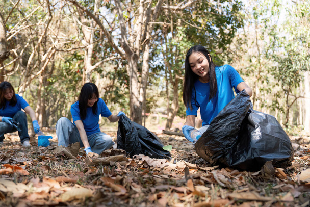 Young people friend volunteer collecting garbage plastic bottles to trash bags. environmental care ecology concept. - Фото, изображение