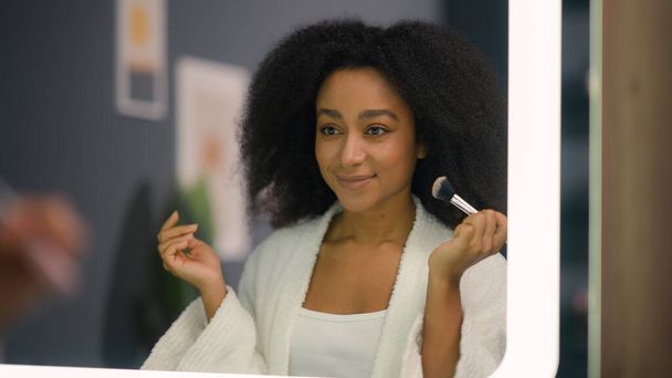 Žena zrcadlo odraz krása vizáž make-up koncept atraktivní biracial etnický krásný afroameričanka dáma dívka v koupelně domácí použít prášek pro obličej péče tón matný příprava kosmetiky - Fotografie, Obrázek