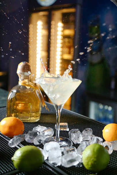 A bottle of alcohol and fresh lemons neatly arranged on a table. - Valokuva, kuva
