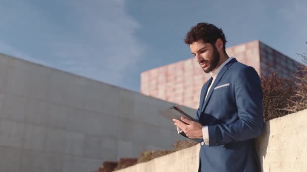 Attractive businessman using digital tablet. Successful hispanic millennial. Modern outdoors. View from below. High quality FullHD footage - Footage, Video
