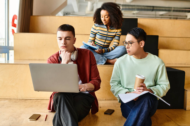 Multicultural group of individuals sitting on stairs, focused on their laptops, engaged in educational activities - Photo, Image