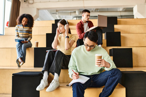 Un gruppo multiculturale di studenti siede su una scala, facendo una pausa in un ambiente educativo. - Foto, immagini