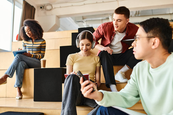 Um grupo multicultural de estudantes se senta confortavelmente em uma escadaria moderna, engajando-se em conversação e relaxamento - Foto, Imagem