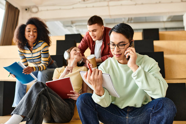 Мультикультурные студенты сидят на полу, поглощенные телефонными разговорами, способствуя связям в образовательной среде - Фото, изображение