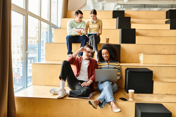 Los estudiantes multiculturales se relajan en los escalones de un edificio moderno, charlando y riendo, abrazando la diversidad - Foto, imagen