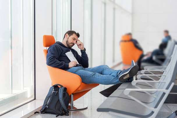 Ο άνθρωπος κοιμάται σε μια αίθουσα αναμονής. Βαρέθηκα να περιμένω τρένο, αεροπλάνο, γιατρό. Απροσεξία των αποσκευών - Φωτογραφία, εικόνα