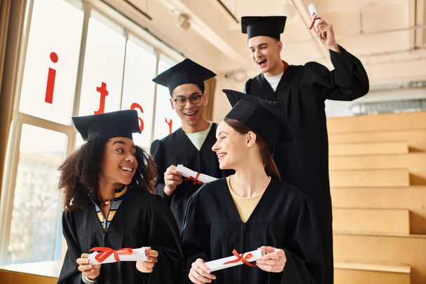 Eine Gruppe unterschiedlicher Studenten im Abschlussgewand mit Diplomen, lächelnd zur Feier ihrer akademischen Errungenschaften. - Foto, Bild