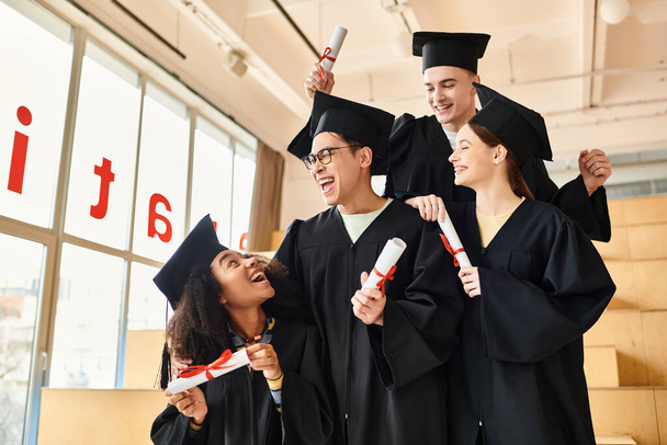 Wielokulturowa grupa szczęśliwych studentów w sukniach dyplomowych. - Zdjęcie, obraz