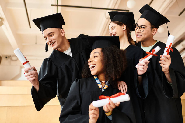 Wielokulturowa grupa szczęśliwych absolwentów w sukniach posiadających dyplomy. - Zdjęcie, obraz