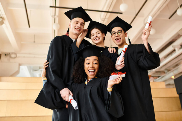 Zróżnicowana grupa studentów w sukniach dyplomowych pozujących z czapkami akademickimi dla niezapomnianego obrazu ich osiągnięć. - Zdjęcie, obraz