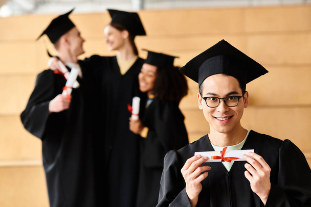 Un hombre diverso en un vestido de graduación triunfante tiene un diploma. - Foto, imagen