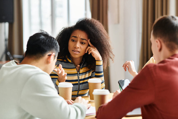 Různorodá skupina studentů zapojených do živé konverzace kolem stolu ve vzdělávacím prostředí. - Fotografie, Obrázek