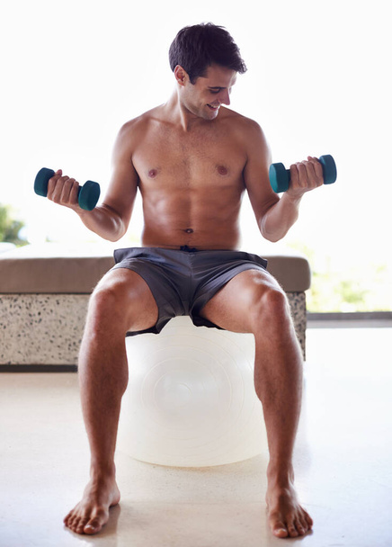 Man, exercise ball and dumbbells for weightlifting, fitness and muscle training for body and self care. Topless athlete, smile and endurance in workout at home for health, wellness and strength. - Photo, Image