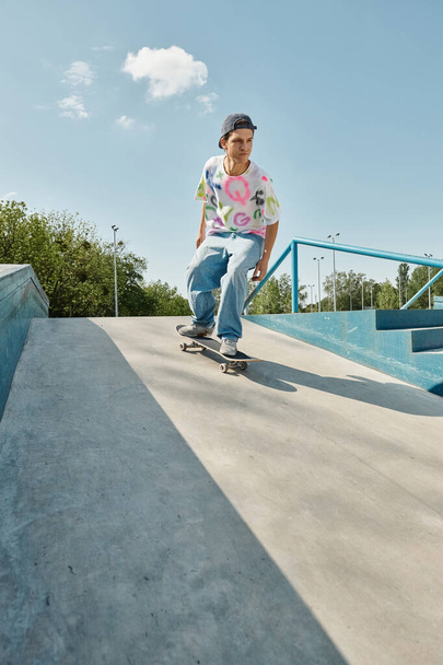Ein junger Skater-Junge fährt an einem sonnigen Sommertag gekonnt mit einem Skateboard die Seite einer Rampe in einem Skatepark hinunter. - Foto, Bild