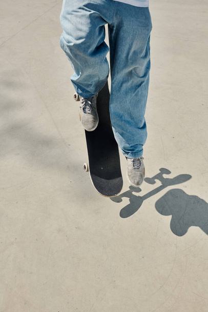 Młody łyżwiarz z wdziękiem jeździ na deskorolce po gładkiej powierzchni cementu w tętniącym życiem skateparku w słoneczny letni dzień. - Zdjęcie, obraz
