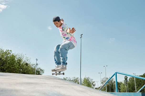 A young skater boy confidently rides his skateboard up the side of a ramp in an outdoor skate park on a sunny day. - Photo, Image