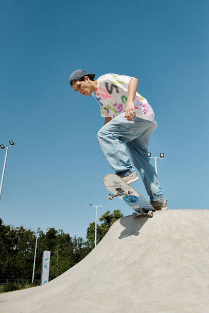 Young skater boy fearlessly rides his skateboard down the ramp in an outdoor skate park on a sunny summer day. - Photo, Image