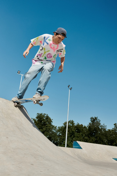 Młody chłopak jeździ na deskorolce po rampie w skateparku w słoneczny letni dzień. - Zdjęcie, obraz