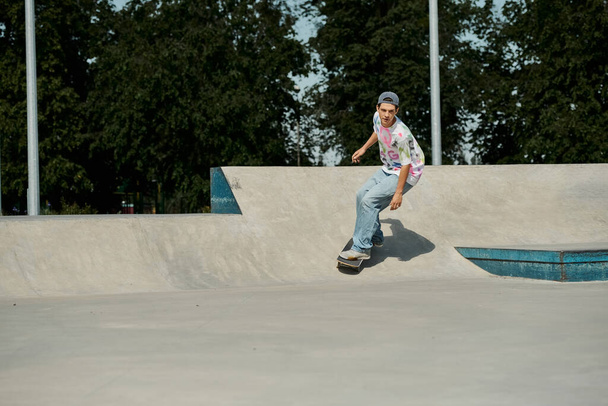 Ένα νεαρό αγόρι σκέιτερ ατρόμητα βόλτες skateboard του μέχρι την πλευρά μιας ράμπας σε ένα πολυσύχναστο υπαίθριο πάρκο skate σε μια ηλιόλουστη μέρα του καλοκαιριού. - Φωτογραφία, εικόνα
