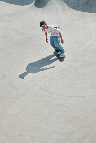 Un joven monta su monopatín por una rampa en un parque de skate en un día soleado de verano. - Foto, imagen