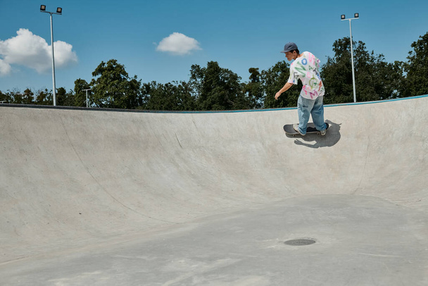 A young skater boy defies gravity, riding his skateboard up the side of a ramp in a vibrant outdoor skate park on a summer day. - Photo, Image
