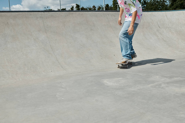 Ein junger Skater-Junge trotzt der Schwerkraft, als er mit seinem Skateboard die Seite einer Rampe in einem sonnigen Skatepark hochfährt. - Foto, Bild