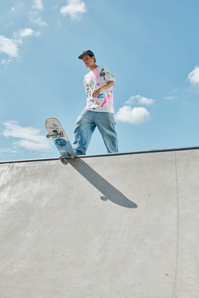 Mladý bruslař chlapec sebevědomě jezdit na skateboardu po straně strmé rampy v slunné venkovní skate park. - Fotografie, Obrázek