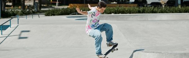 Ein junger Mann fährt an einem sonnigen Sommertag gekonnt mit seinem Skateboard die Seite einer Rampe in einem Skatepark hinauf. - Foto, Bild