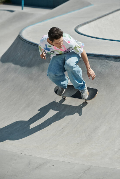 Νεαρό αγόρι σκέιτερ βόλτες skateboard μέχρι ράμπα σε ζωντανή εξωτερική πάρκο skate σε μια ηλιόλουστη μέρα του καλοκαιριού. - Φωτογραφία, εικόνα