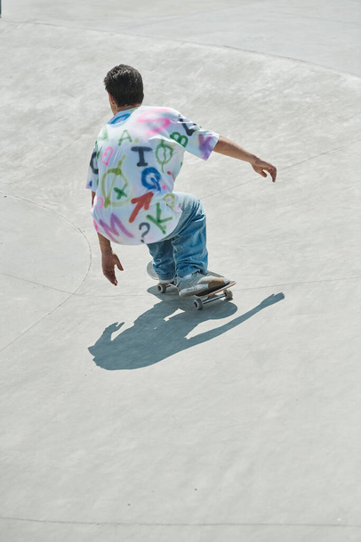 Ein junger Skater-Junge fährt an einem sonnigen Sommertag selbstbewusst mit einem Skateboard eine Betonrampe in einem lebhaften Outdoor-Skatepark hinunter. - Foto, Bild