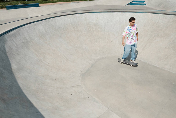 Ein junger Mann fährt an einem sonnigen Sommertag gekonnt sein Skateboard in einem lebhaften Skatepark und zeigt seine Tricks und sein Talent. - Foto, Bild