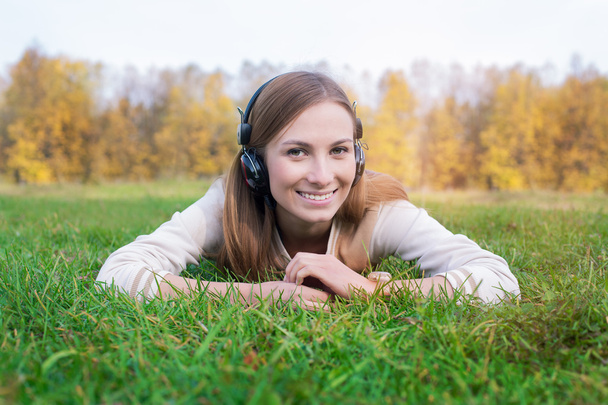 Φοιτητής ακούγοντας ακουστικά και ψέματα για την πράσινη χλόη - Φωτογραφία, εικόνα