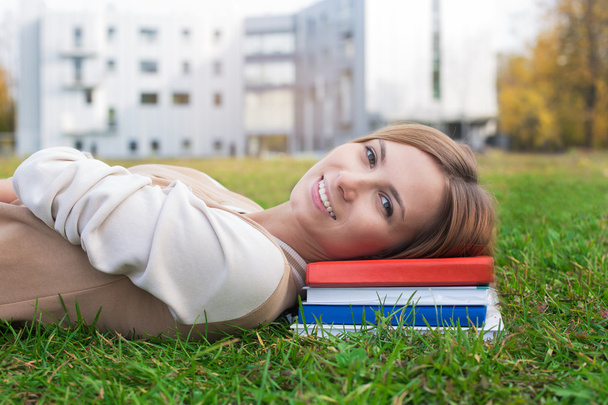 Студент лежить на зеленій траві та книгах
 - Фото, зображення