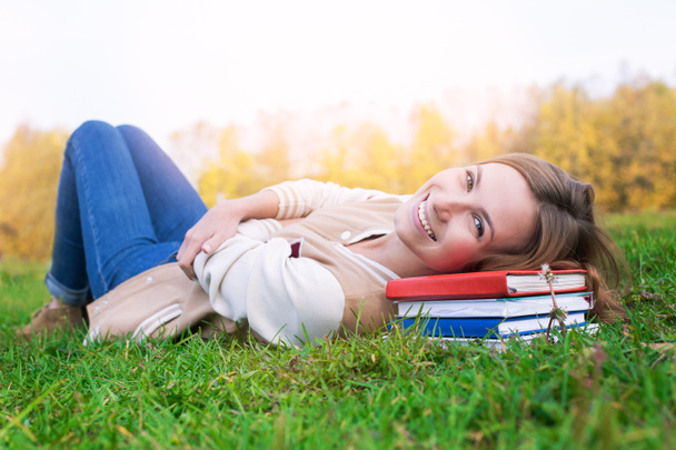 Студент лежить на зеленій траві і книгах і дивиться вгору
 - Фото, зображення
