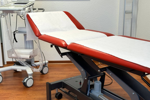 Červená pojízdná postel pokrytá papírovým ručníkem v ordinaci lékařů. Detailní záběr. - Fotografie, Obrázek