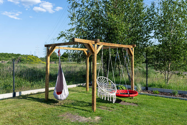 A modern cubic playground made of wooden logs and metal corners, a visible rocker and a nest. - Foto, afbeelding