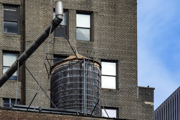 Ein hölzerner Wassertank in einem typischen Gebäude in Manhattan, um einen Teil des Big Apple zu versorgen und die typischen Gebäude der Stadt New York (USA)). - Foto, Bild