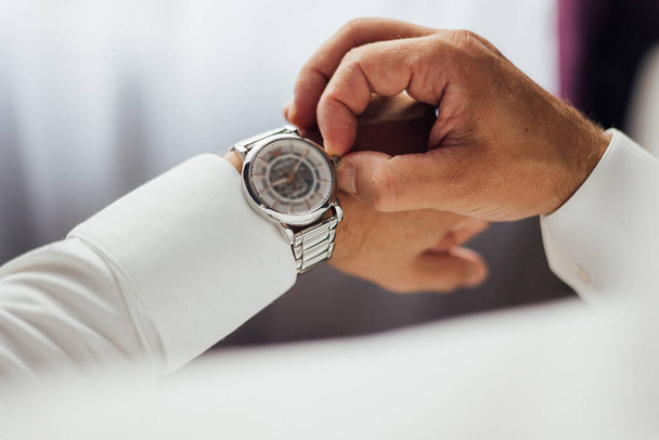 homme d'affaires vérifiant l'heure sur sa montre-bracelet, homme mettant horloge sur la main, marié se préparer le matin avant la cérémonie de mariage - Photo, image