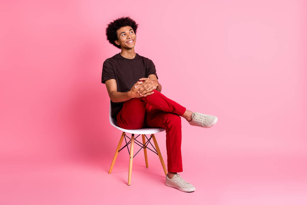Full body size photo of young relaxed guy sitting on stool comfortable pose dreamy looking novelty isolated over pink color background. - Foto, Imagen