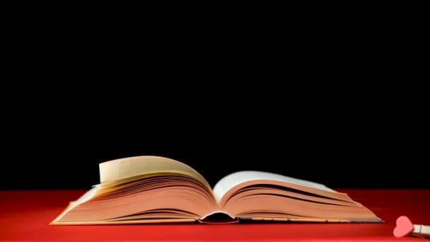 Capovolgere rapidamente le pagine di un libro spesso su uno sfondo nero rosso. - Filmati, video