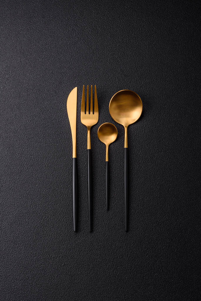 Posate forchetta, coltello e cucchiaio su uno sfondo di cemento con texture scura. Articoli da cucina e accessori - Foto, immagini