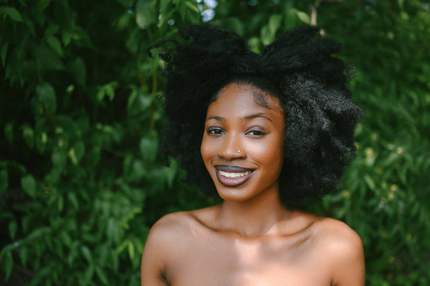 Kapalı portre Güzel Afro-Amerikan kadın mükemmel beyaz dişler dışarıda gülümsüyor, güneşli yaz günü yeşil yapraklar. Yüz bakımı. Kozmetoloji, cilt bakımı ve kaplıca - Fotoğraf, Görsel