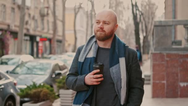 Images de l'homme barbu en manteau marchant dans la rue de la vieille ville et buvant une tasse de café pour aller. - Séquence, vidéo