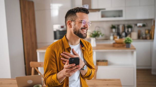 άνθρωπος με γυαλιά σταθεί στο σπίτι χρήση κινητό τηλέφωνο sms γραπτών μηνυμάτων - Φωτογραφία, εικόνα